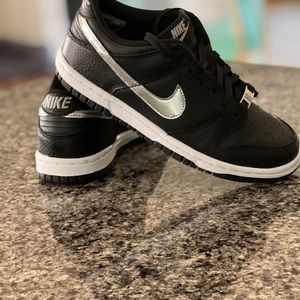 NIKE Dunk Low, Black sneakers, silver Swoosh decals, and diamond decal on lace.